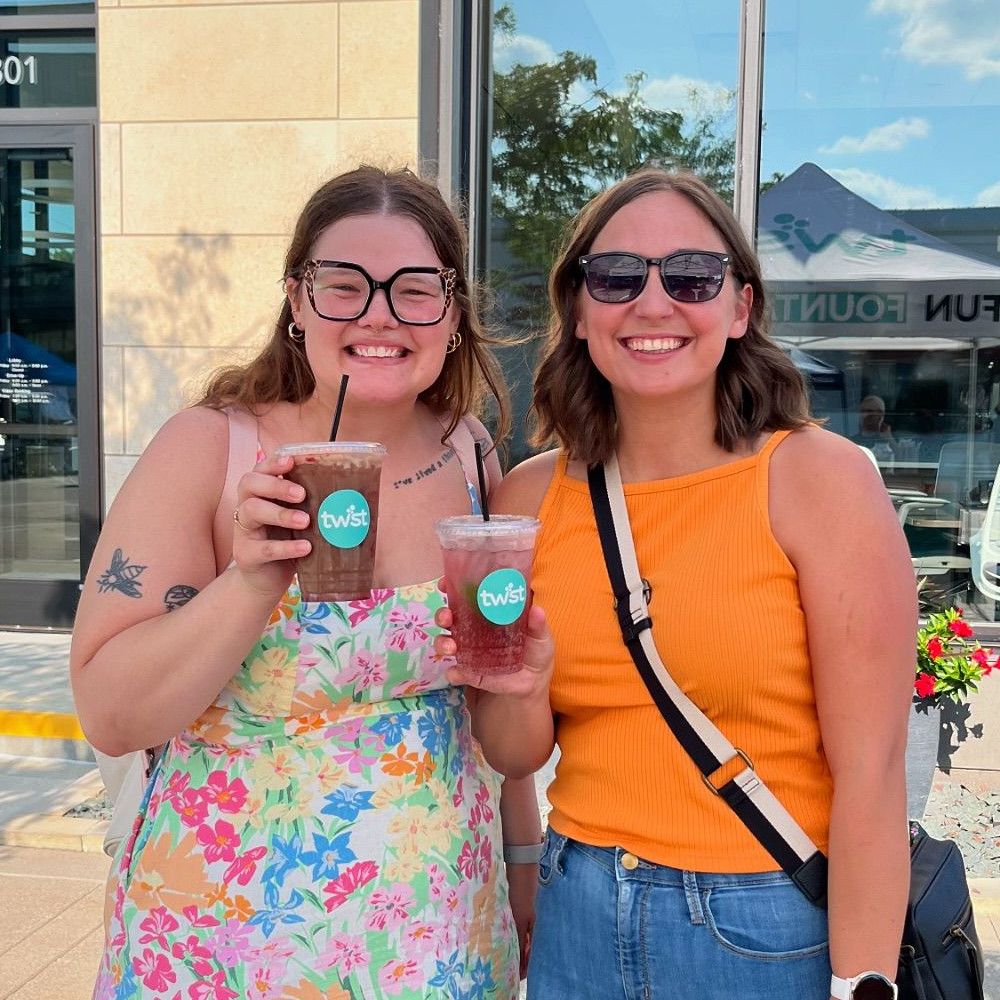 2 people holding their Twist drinks and smiling in Downtown Des Moines