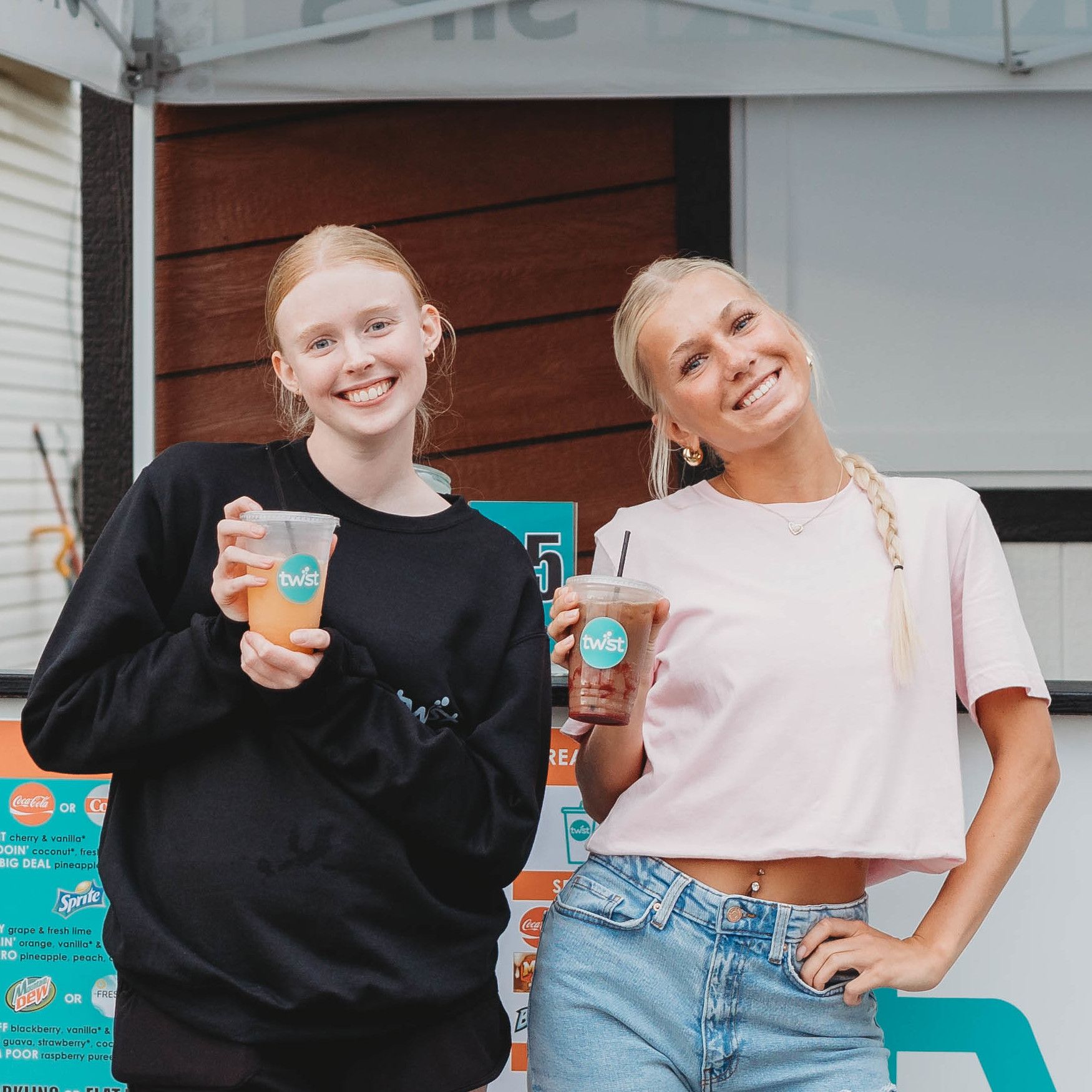 2 people holding their Twist drinks and smiling in front of Twist's mobile cart